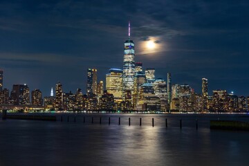 Wall Mural - Beautiful view of Manhattan city at nighttime with a full moon.