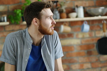 Handsome young man with beard posing on the kitchen