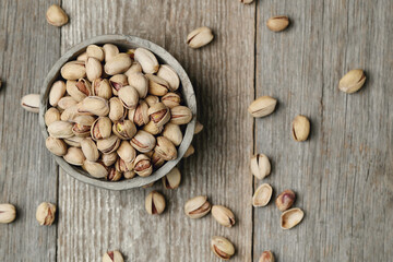 Top view of pistachio nuts in gray bowl isolated on a wooden background.