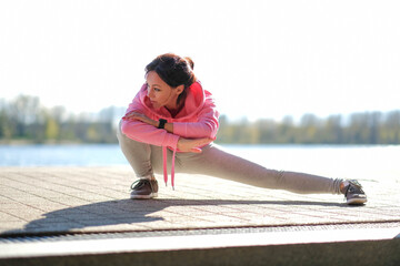 Wall Mural - Young beautiful girl in sportswear stretches outdoor