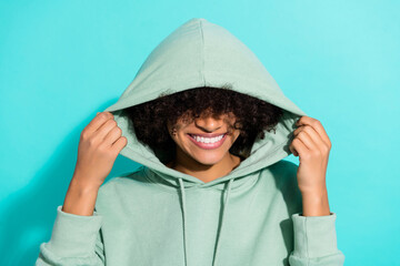 Photo of positive satisfied person arms touch put hood head beaming smile isolated on cyan color background