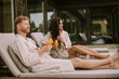Young couple relaxing on beds and drinking fresh orange juice on the outdoor terrace