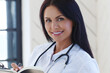 © racool_studio - Professional,confident female-doctor with stethoscope  filling up a form of patient.