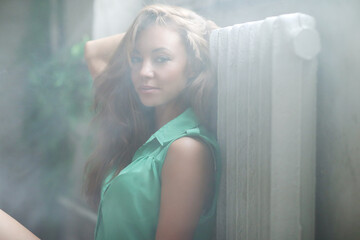 Wall Mural - Close-up portrait of a beautiful,young,relaxed lady in green dress sitting on the wooden floor.