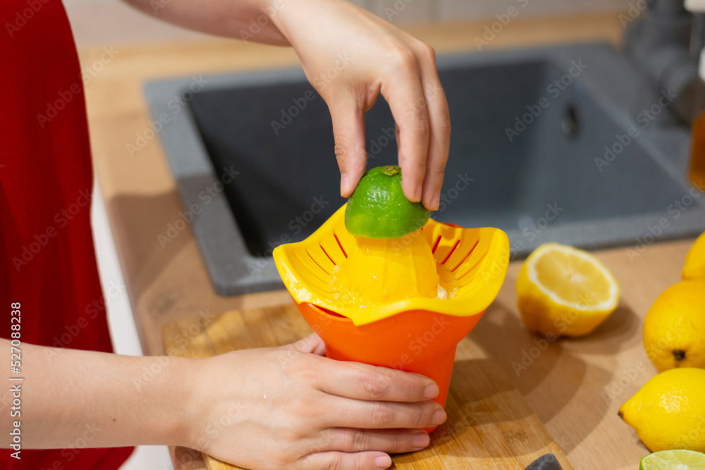 Close-up woman no face squeezes limes on the kitchen table oranges ...