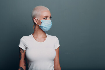 Millenial young woman in medical protective face mask with short blonde hair portrait standing indoor