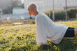© primipil - Portrait of young smiling millenial european short haired woman doing plank bar on green grass meadow summer park. Beautiful happy blonde girl outdoor.