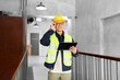 © Syda Productions - architecture, construction business and building concept - happy smiling male supervisor in helmet and safety west with tablet pc computer at office