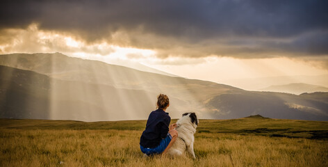 Poster - woman and dog watching amazing panorama of heavenly lights at sunset in high mountains