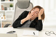 © Vitaliy - Young sleepy business woman yawning and working on laptop in the office. Busy and productive workday