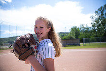 Portrait Of Serious Middle School Girl Softball Player With Baseball Glove In Outfield