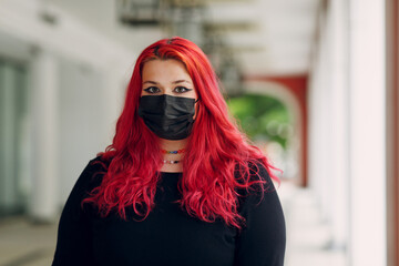 Wall Mural - European plus size woman portrait in face mask outdoor street city. Young red pink haired body positive girl.