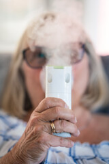 senior lady breathing through oxygen inhaler at home. medical and treatment concept.