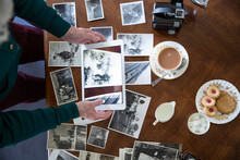 Overhead View Of Senior Woman Looking At Old Photographs And Drinking Tea
