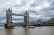 © Klodien - London, England, UK - July 6, 2022: Tower bridge seen from Tower of London quay under heavy cloudscape. Boats on brown Thames and traffic on bridge.