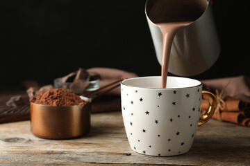 Wall Mural - Pouring hot cocoa drink into cup on wooden table