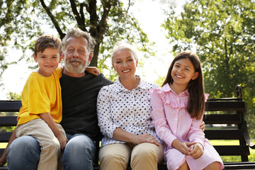 Happy grandparents with little children resting together in park