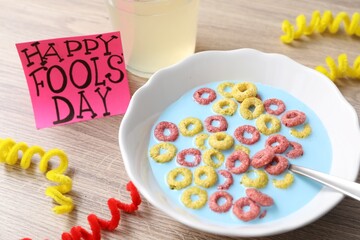 Wall Mural - Plate of corn rings with light blue milk, drink and words Happy Fool's Day on wooden table