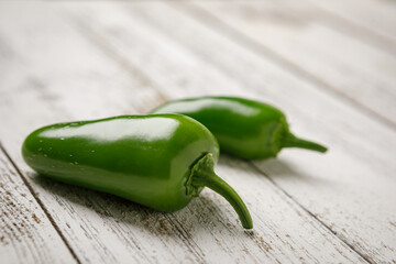 Wall Mural - Whole green organically homegrown jalapeno peppers on a white washed wooden background