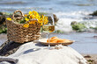 © The Picture Pantry - glass with white wine on stone stools against blue sea and waves, summer picnic concept