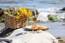 Glass With White Wine On Stone Stools Against Blue Sea And Waves, Summer Picnic Concept