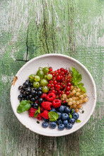 Mix Of Fresh Berries With Leaves In Vintage Ceramic Colander