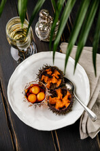 Fresh Opened Sea Urchins With Quail Egg And Soy Sauce On White Plate On Black Wooden Table