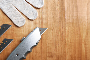 Canvas Print - Utility knife, blades and glove on wooden table, flat lay. Space for text