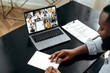 © Kateryna - African american male smart student listening to the online lecture, taking notes in notebook, on the laptop screen are teacher and a group of multiracial students. Online training, lecture, seminar