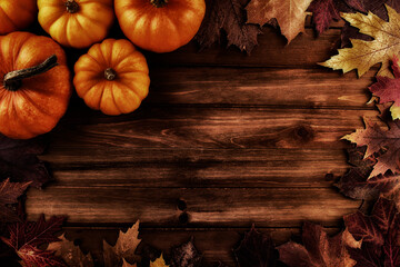 Wall Mural - Pumpkins with fall leaves over wooden background. Top view.