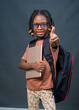 © kehinde - A female African girl child or kid student from Nigeria happily doing thumbs up to the camera while carrying an education smart tablet in her hands and a school back on her back