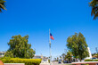 an American flag flying on a flag pole surrounded by lush tree trees, grass and plants at La Bella Fontana Park in Long Beach California USA