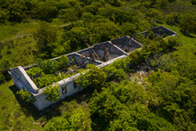 Ruins Of An Old Abandoned Building In A Thicket Of Grass And Shrubs