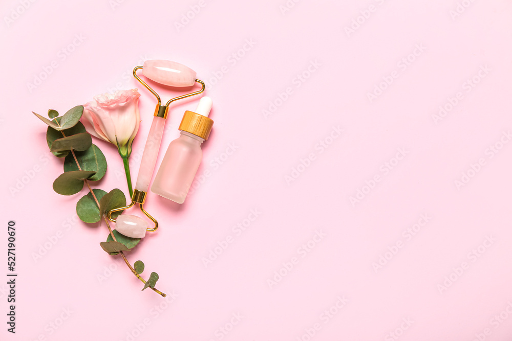 Facial massage tool with cosmetic bottle, eucalyptus and rose on pink background