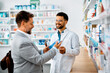 © Drazen - Happy pharmacist assists his customer in choosing products in pharmacy.