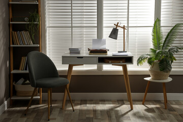 Comfortable writer's workplace interior with typewriter on desk in front of window