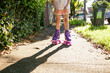 © Austockphoto - Girl wearing pink shorts with purple roller skates with pink wheels on the side walk