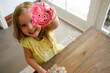 © Austockphoto - Smiling girl with blonde hair wearing yellow blouse raising a pink transparent piggy bank