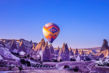 Hot Air Balloon In The Blue Sky In Front Of Bizarre Mountain Silhouettes In The Cappadocia Valley In The Early Morning.