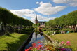 Eegracht canal surrounded by beautiful gardens in IJlst, Friesland, Netherlands, with Mauritiuskerk church in the background