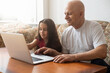 © Angelov - Grandfather and granddaughter spend time together use laptop, browse website, younger generation teach explain to older how to use modern tech concept