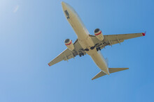 Looking Up At The Under Carriage Of A Large Jet As It Flies Overhead In A Blue Sky
