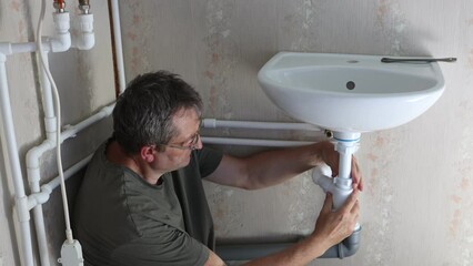 Wall Mural - Repairer fixes leak in drain pipe by replacing siphon.