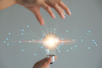 Fototapete - woman's hand holding a light bulb technology ,using new technology to find new ideas