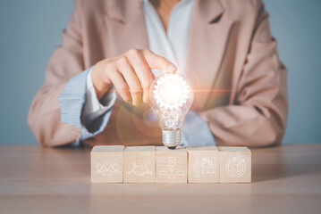 Fototapete - business woman's hand holding a light bulb driven by multiple gears inside, collaborating to find new ideas