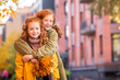 © Maria Moroz - Two red-haired girls, sisters, cheerfully walk along the city street during the golden autumn leaf fall.