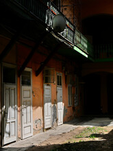 Interior Courtyard Of A Building With Light And Shadow. Orange Walls, Wooden Doors And A Satellite Dish Hanging From A Balcony. For Background.