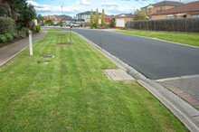 Freshly Mown Grass At A Nature Strip On A Suburban Road With Some Residential Houses In The Distance. Australian Neighborhood Street In A Suburb. Melbourne, VIC Australia.