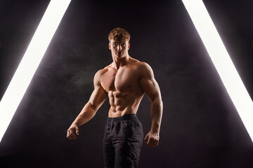 the torso of attractive muscular male body builder on black background.
