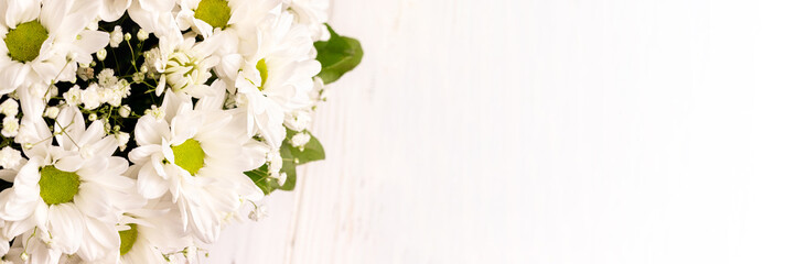 Wall Mural - Bouquet of white chamomile chrysanthemums on white background banner with copy space. Wide panoramic header. Gift flowers basket for the holiday